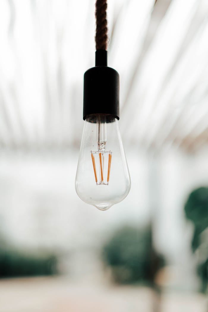 Low angle of vintage light bulb hanging from ceiling on rope in stylish room